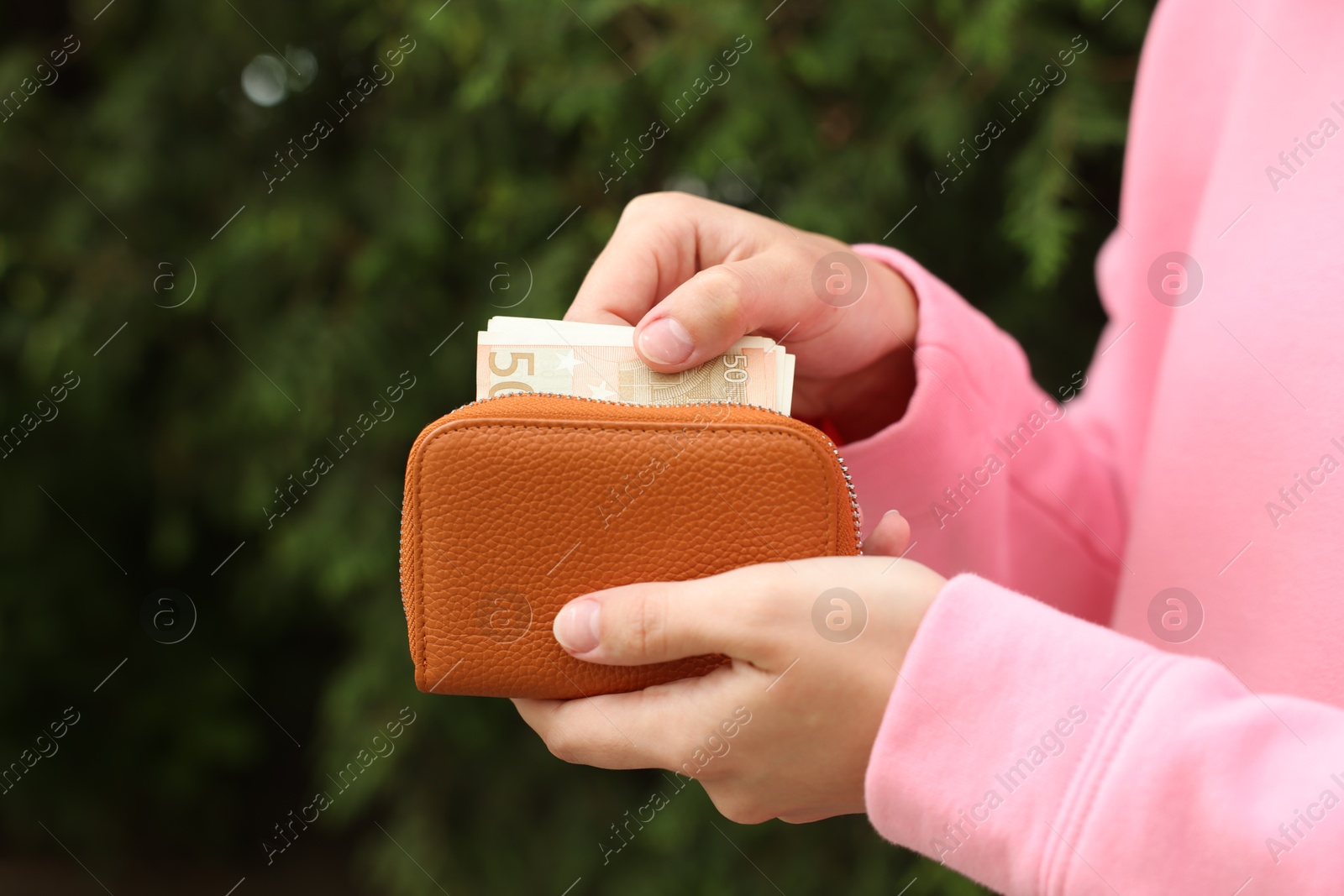 Woman putting money into wallet outdoors, closeup Photo of Woman putting money into wallet outdoors, closeup