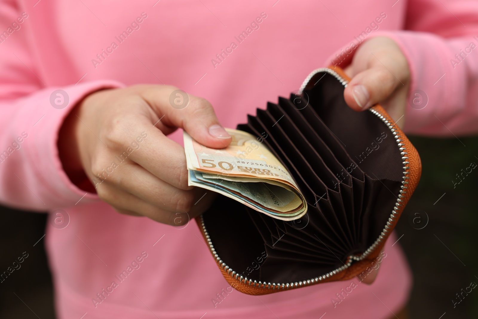 Woman putting money into wallet outdoors, closeup Photo of Woman putting money into wallet outdoors, closeup