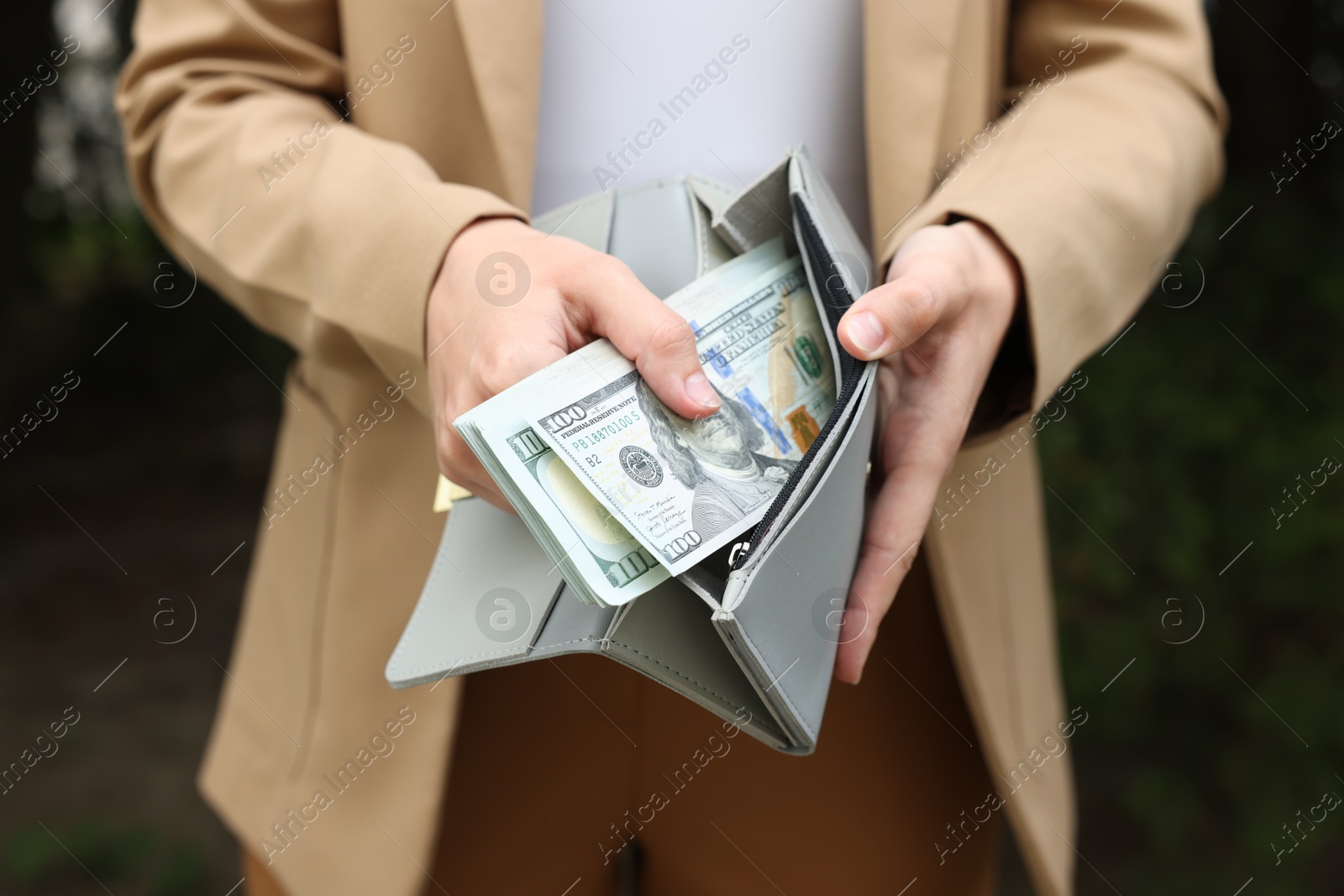 Woman putting money into wallet outdoors, closeup Photo of Woman putting money into wallet outdoors, closeup