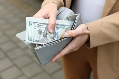 Photo of Woman putting money into wallet outdoors, closeup