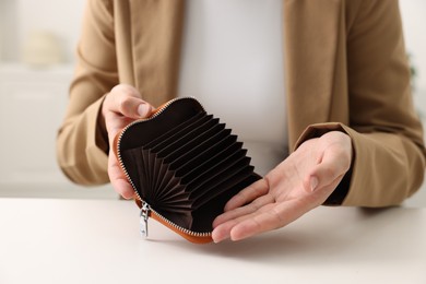 Photo of Woman with empty wallet at white table, closeup