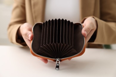 Photo of Woman with empty wallet at white table, closeup