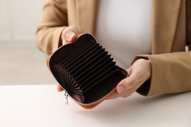 Photo of Woman with empty wallet at white table, closeup