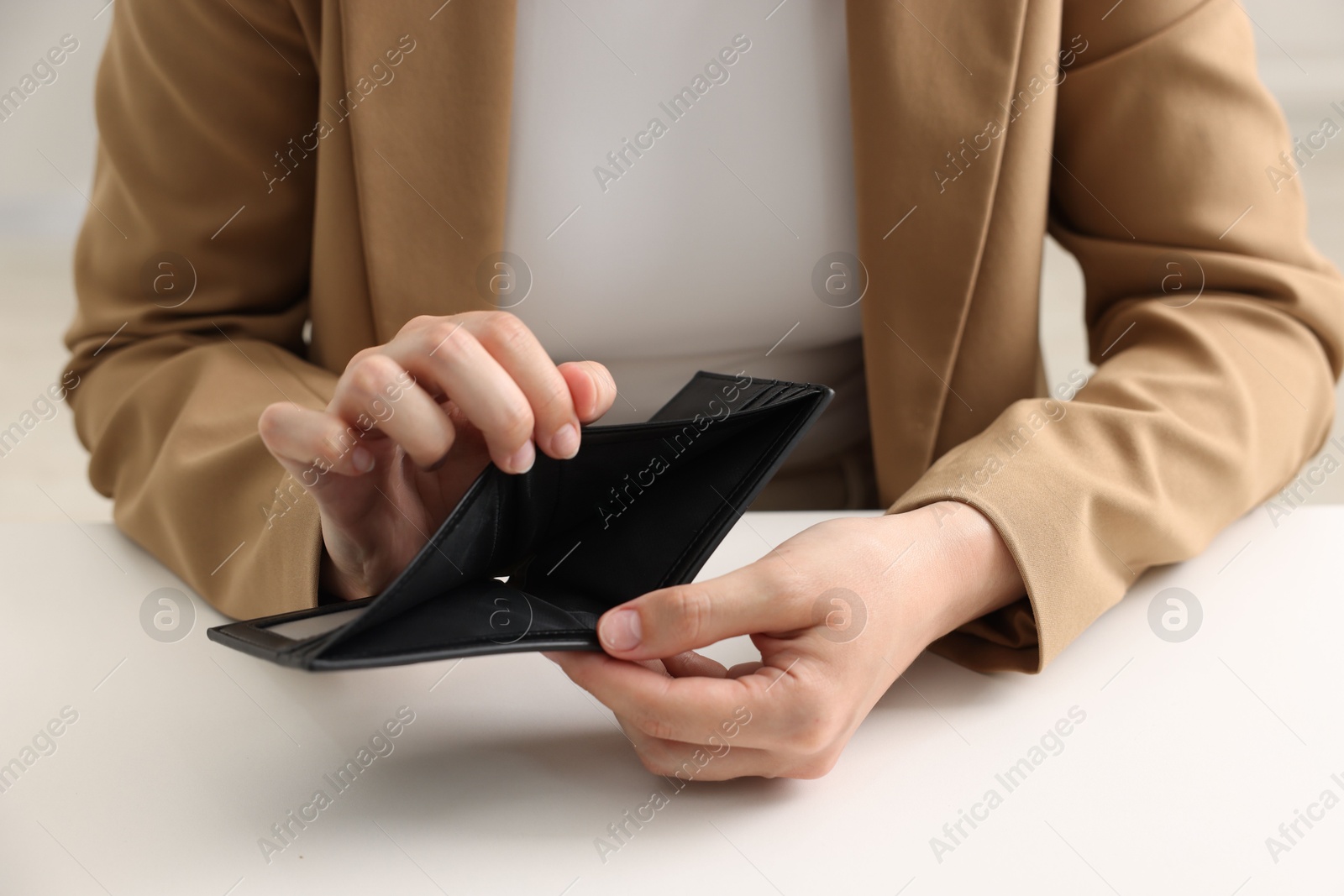 Woman with empty wallet at white table, closeup Photo of Woman with empty wallet at white table, closeup