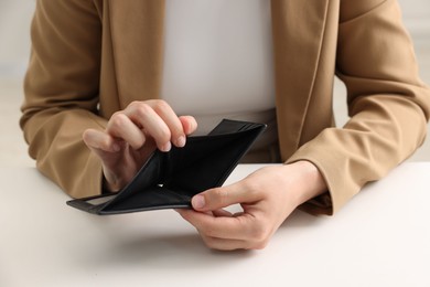 Photo of Woman with empty wallet at white table, closeup