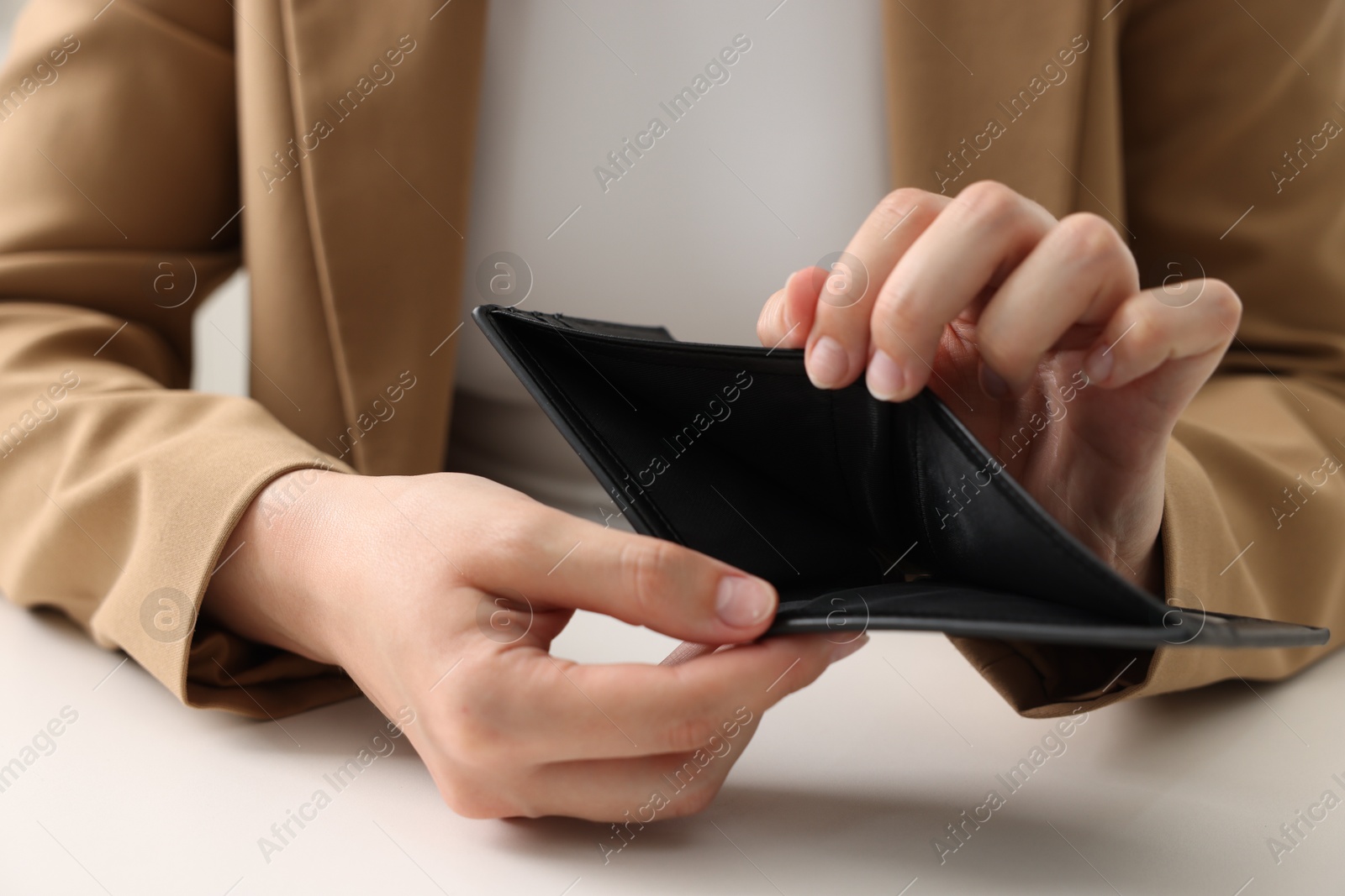 Woman with empty wallet at white table, closeup Photo of Woman with empty wallet at white table, closeup
