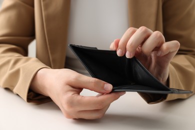 Photo of Woman with empty wallet at white table, closeup