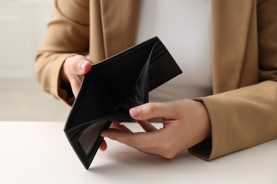 Photo of Woman with empty wallet at white table, closeup