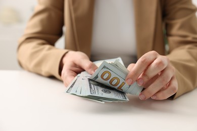 Photo of Woman counting money at white table, closeup