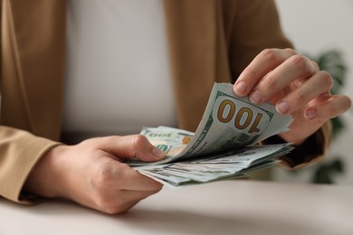 Photo of Woman counting money at white table, closeup