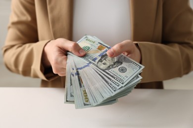 Photo of Woman counting money at white table, closeup