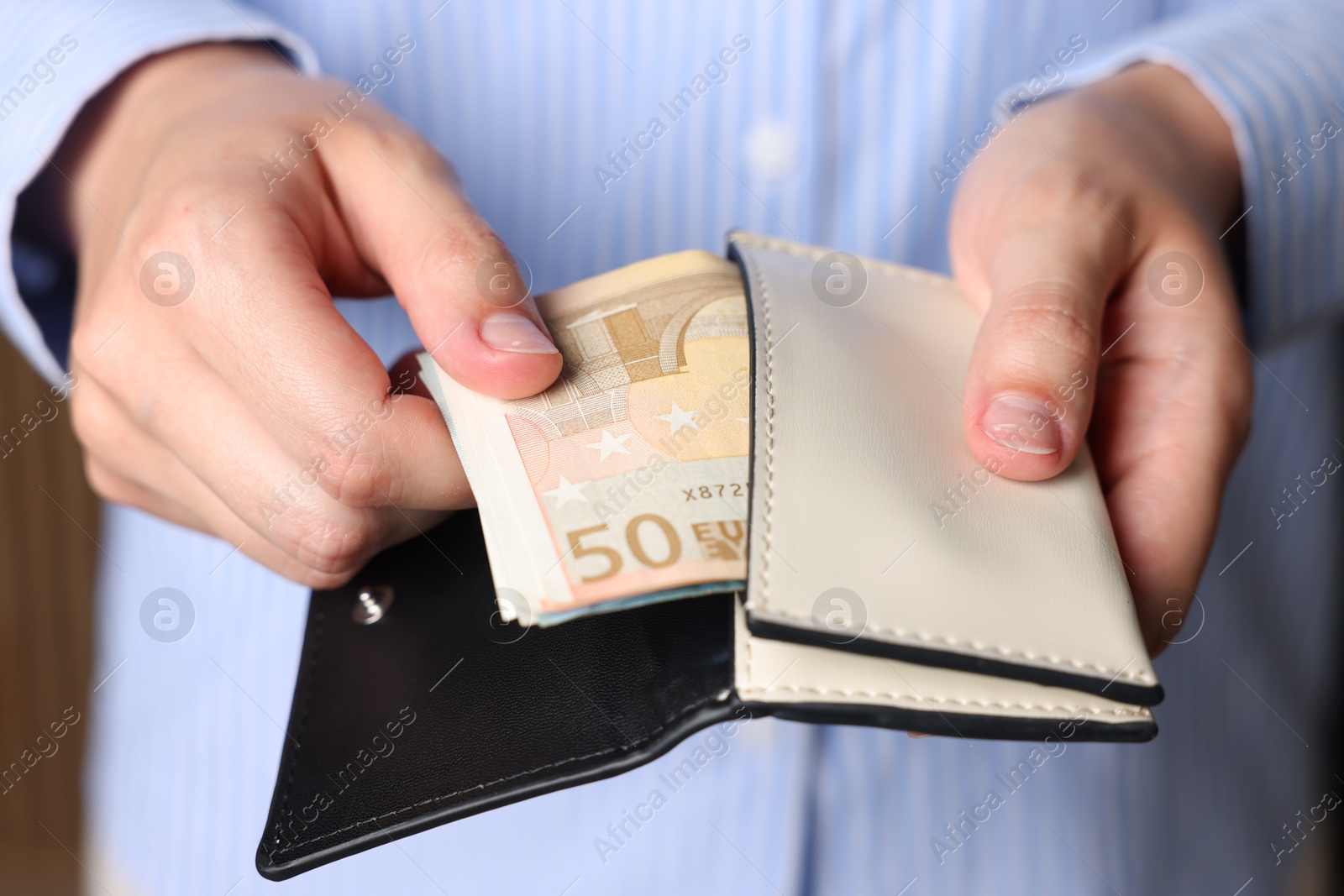 Woman putting money into wallet indoors, closeup Photo of Woman putting money into wallet indoors, closeup