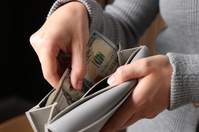 Photo of Woman putting money into wallet indoors, closeup
