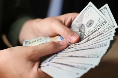 Photo of Woman counting money at table indoors, closeup