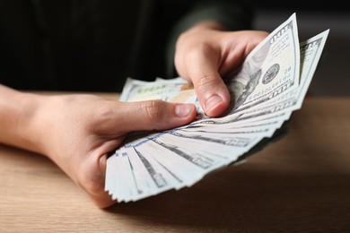 Photo of Woman counting money at wooden table, closeup
