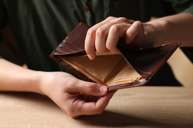 Photo of Woman with empty wallet at wooden table, closeup
