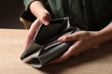 Photo of Woman with empty wallet at wooden table, closeup