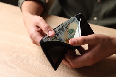 Photo of Man counting money at wooden table, closeup