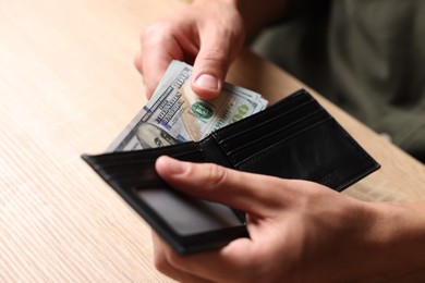 Photo of Man counting money at wooden table, closeup