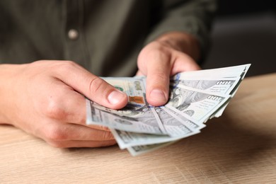 Photo of Man counting money at wooden table, closeup