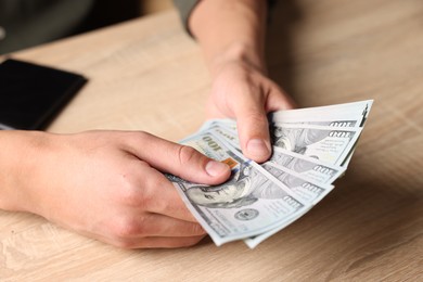 Photo of Man counting money at wooden table, closeup