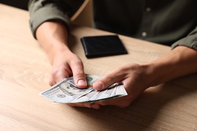 Photo of Man counting money at wooden table, closeup