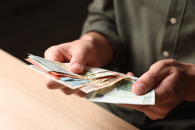 Photo of Man counting money at wooden table, closeup