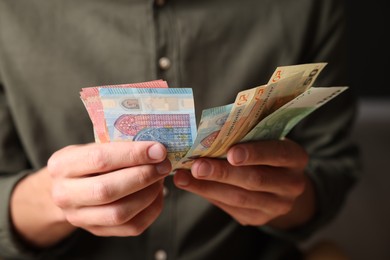 Photo of Man counting his money indoors, closeup view