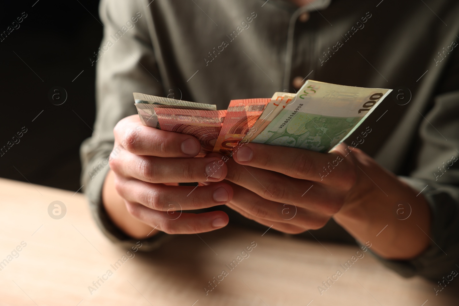 Photo of Man counting money at wooden table, closeup