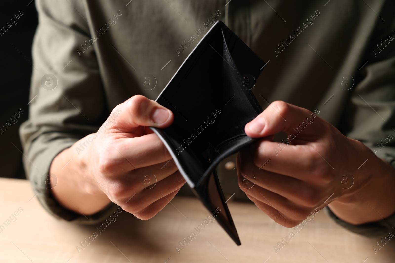 Man with empty wallet at wooden table, closeup Photo of Man with empty wallet at wooden table, closeup
