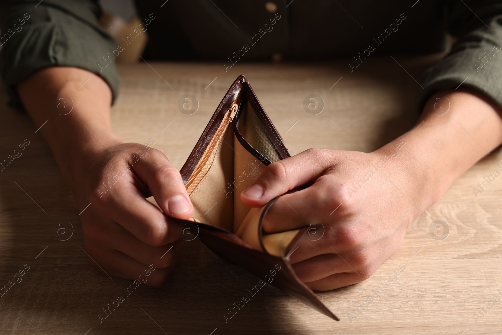 Man with empty wallet at wooden table, closeup Photo of Man with empty wallet at wooden table, closeup