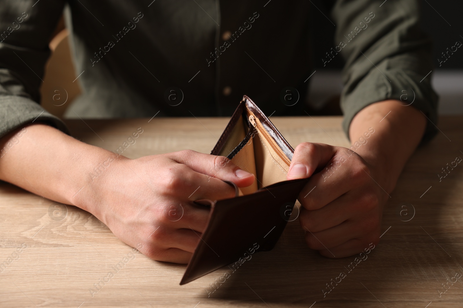 Man with empty wallet at wooden table, closeup Photo of Man with empty wallet at wooden table, closeup