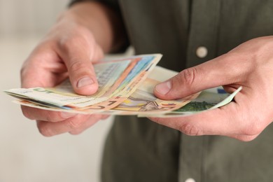 Photo of Man counting his money indoors, closeup view