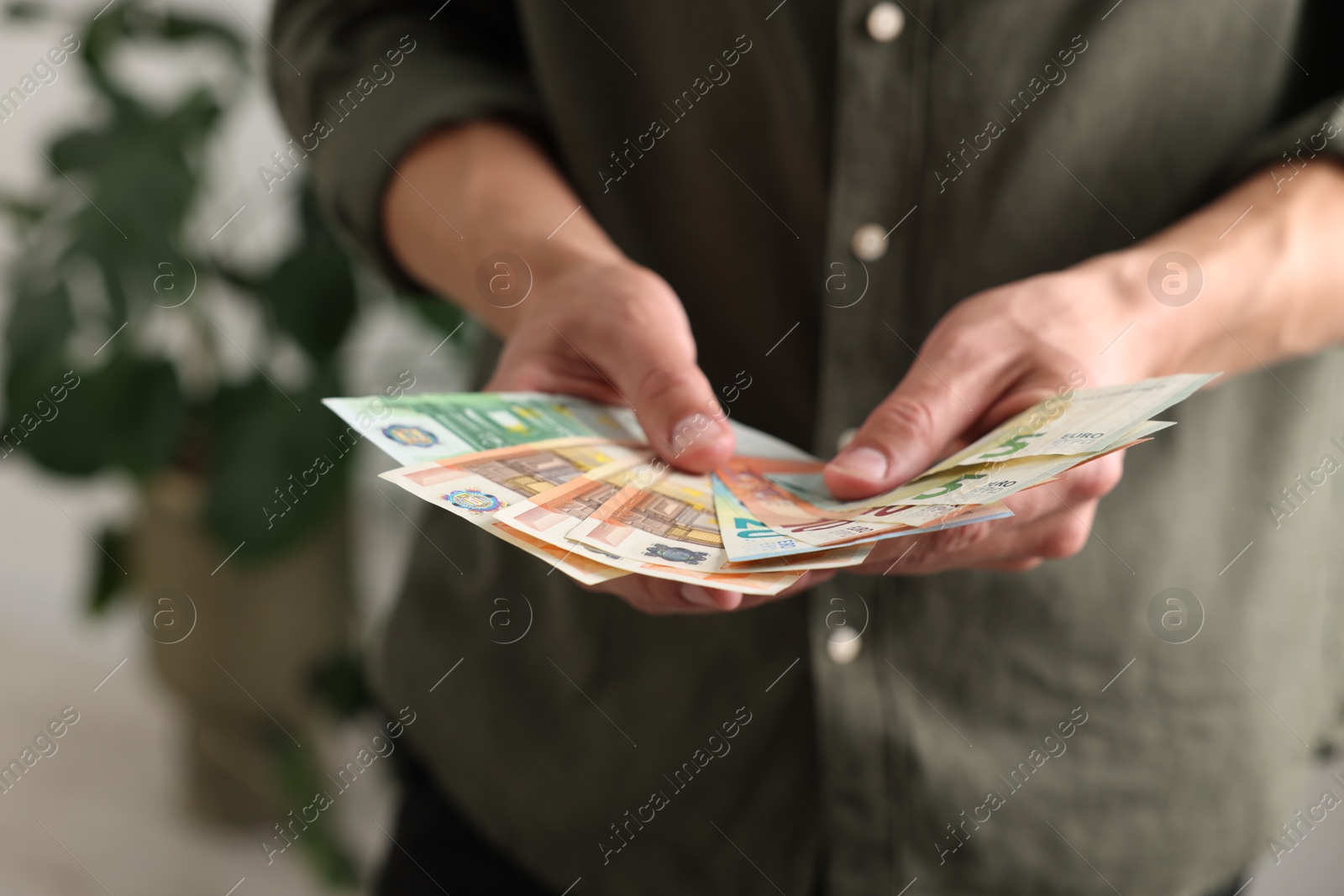 Man counting his money indoors, closeup view Photo of Man counting his money indoors, closeup view