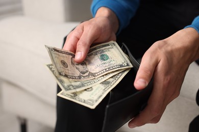 Photo of Man putting money into wallet indoors, closeup