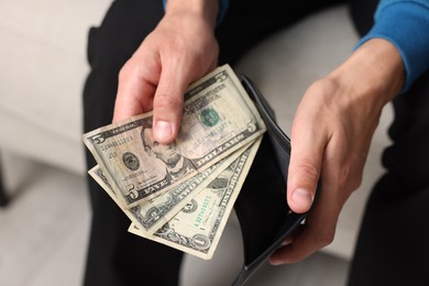 Photo of Man putting money into wallet indoors, closeup
