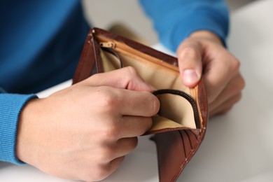 Photo of Man with empty wallet at white table, closeup