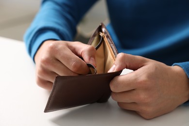 Photo of Man with empty wallet at white table, closeup