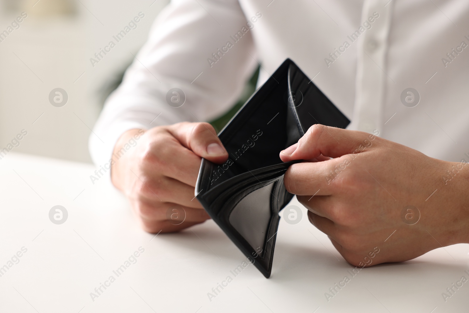 Photo of Man with empty wallet at white table, closeup