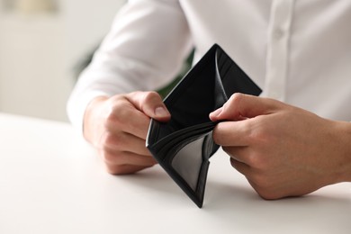 Photo of Man with empty wallet at white table, closeup
