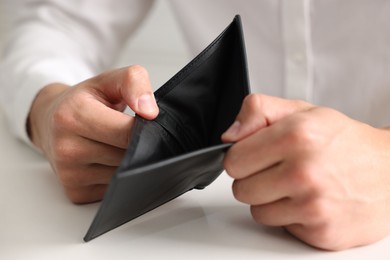 Photo of Man with empty wallet at white table, closeup