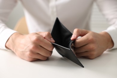 Photo of Man with empty wallet at white table, closeup