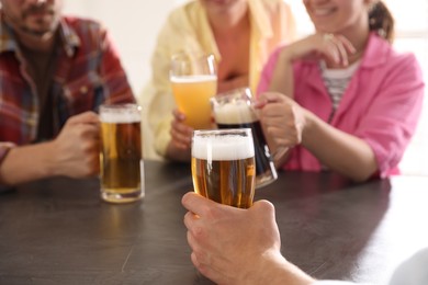 Photo of Friends with glasses of beer at grey table indoors, selective focus
