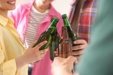 Photo of Friends clinking bottles of beer indoors, closeup