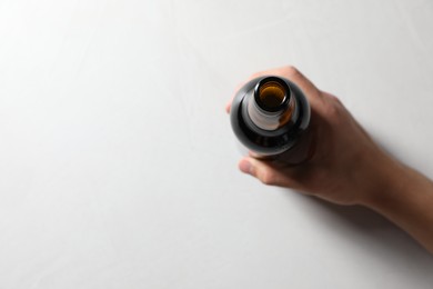 Photo of Man with bottle of beer at white table, top view. Space for text