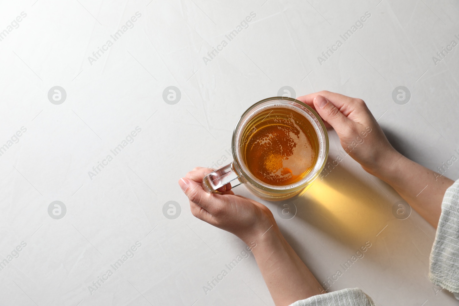 Photo of Woman with glass mug of beer at white table, top view. Space for text