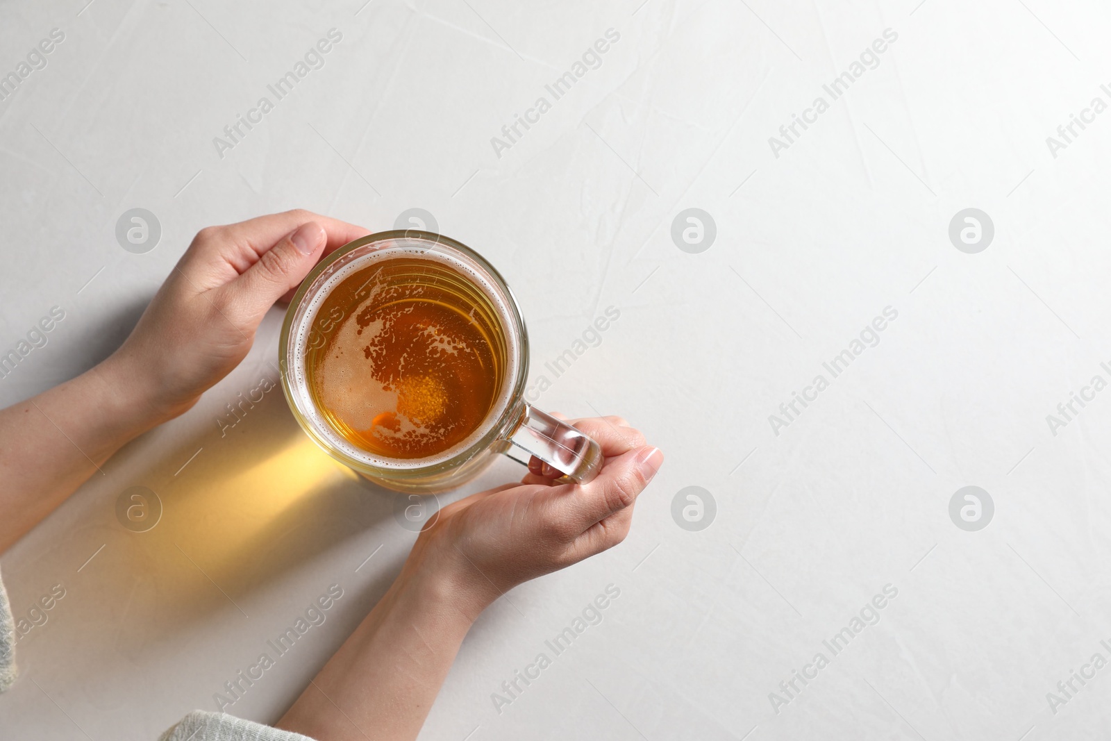 Photo of Woman with glass mug of beer at white table, top view. Space for text