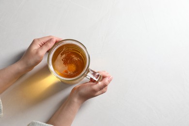 Photo of Woman with glass mug of beer at white table, top view. Space for text