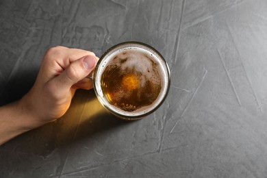 Photo of Man with glass mug of beer at grey table, top view. Space for text