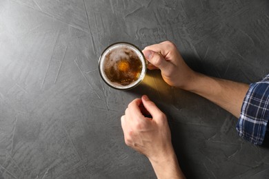 Photo of Man with glass mug of beer at grey table, top view. Space for text